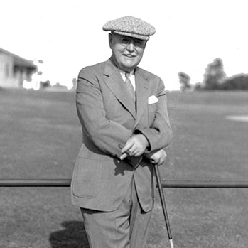 man standing with golf club and cigar